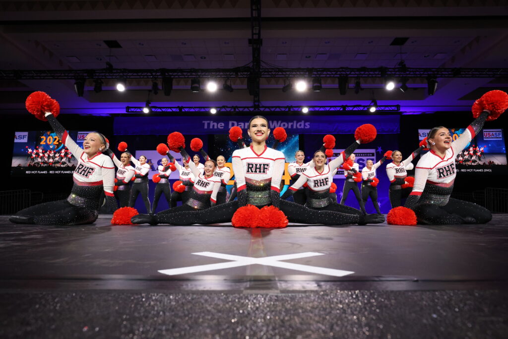 Dancers with red poms in their dance in the end pose of their Maddie Jamieson choreography dance team routine.